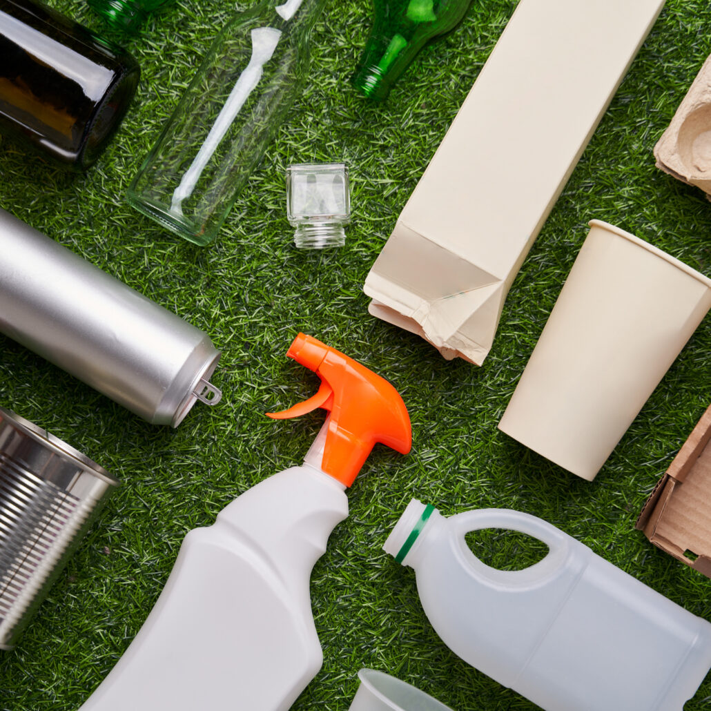 A selection of garbage for recycling. Segregated glass, metal, plastic and paper on green grass background. Concept of zero waste, eco lifestyle and sustainable living